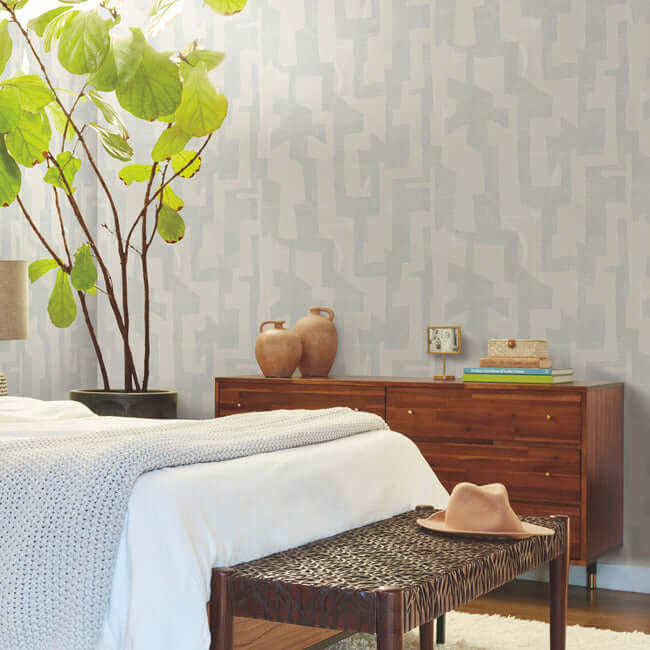 Modern Tribal wallpaper by Nikki Chu featuring a soft grey textured background with bold geometric tribal patterns in steel-blue tones. A contemporary non-woven wallcovering designed for modern interiors, accent walls, bedrooms, living rooms, and office spaces with a stylish artistic and textured finish.