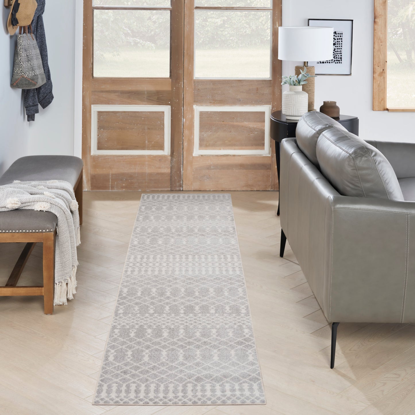 Gray geometric runner rug on a light wood floor in a modern living room with a gray sofa and bench.