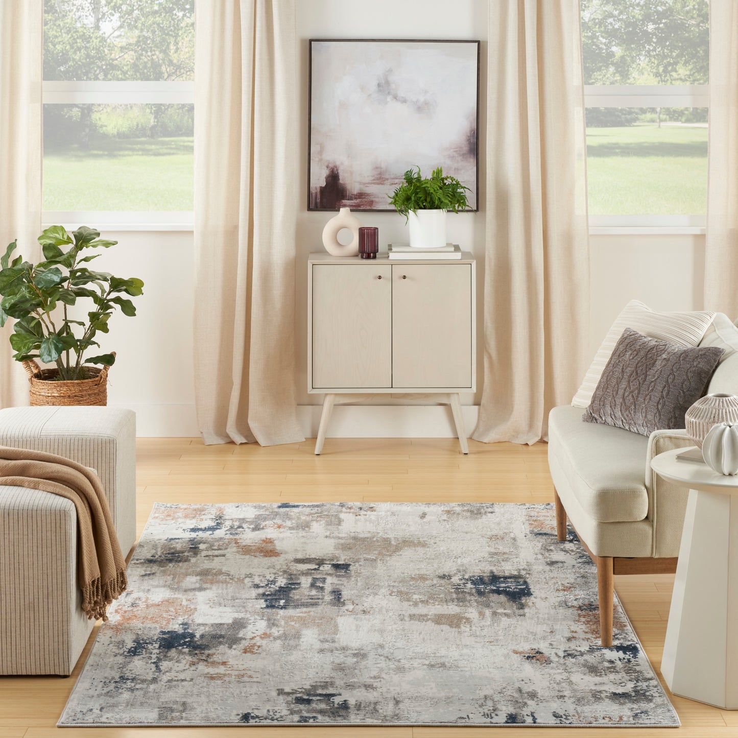 Neutral living room with beige curtains, abstract art, light wood cabinet, plant, cream sofa, and a gray-blue abstract rug.
