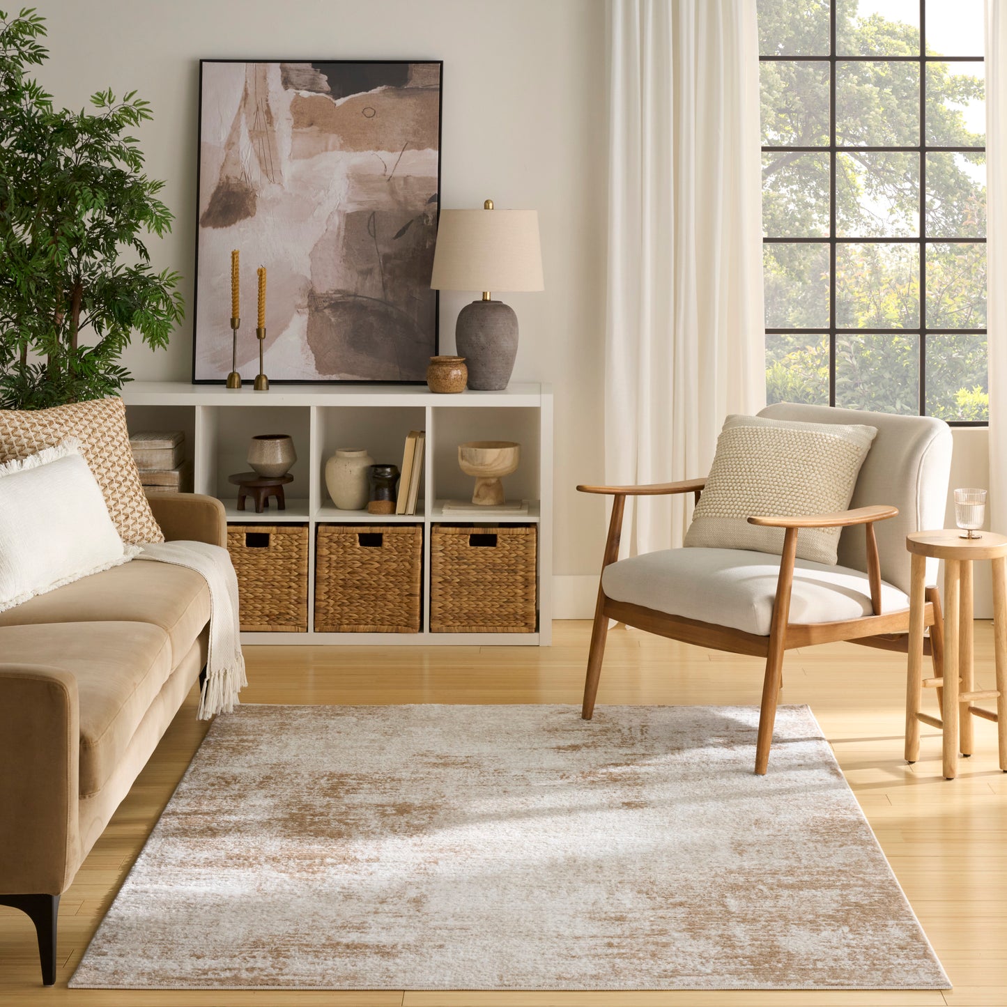 Neutral living room with beige sofa, mid-century armchair, cubby shelf, wicker baskets, abstract art, and beige rug.