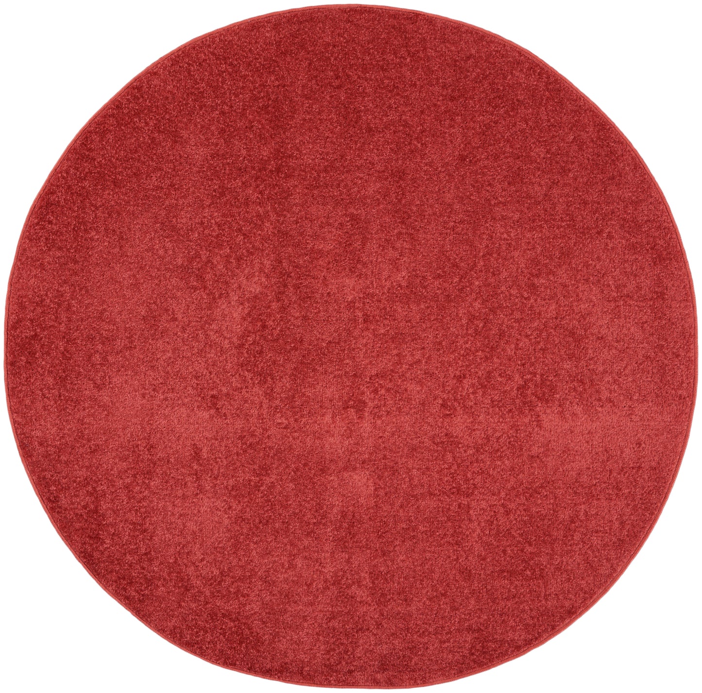 Round red plush rug with velvety texture for cozy living spaces.