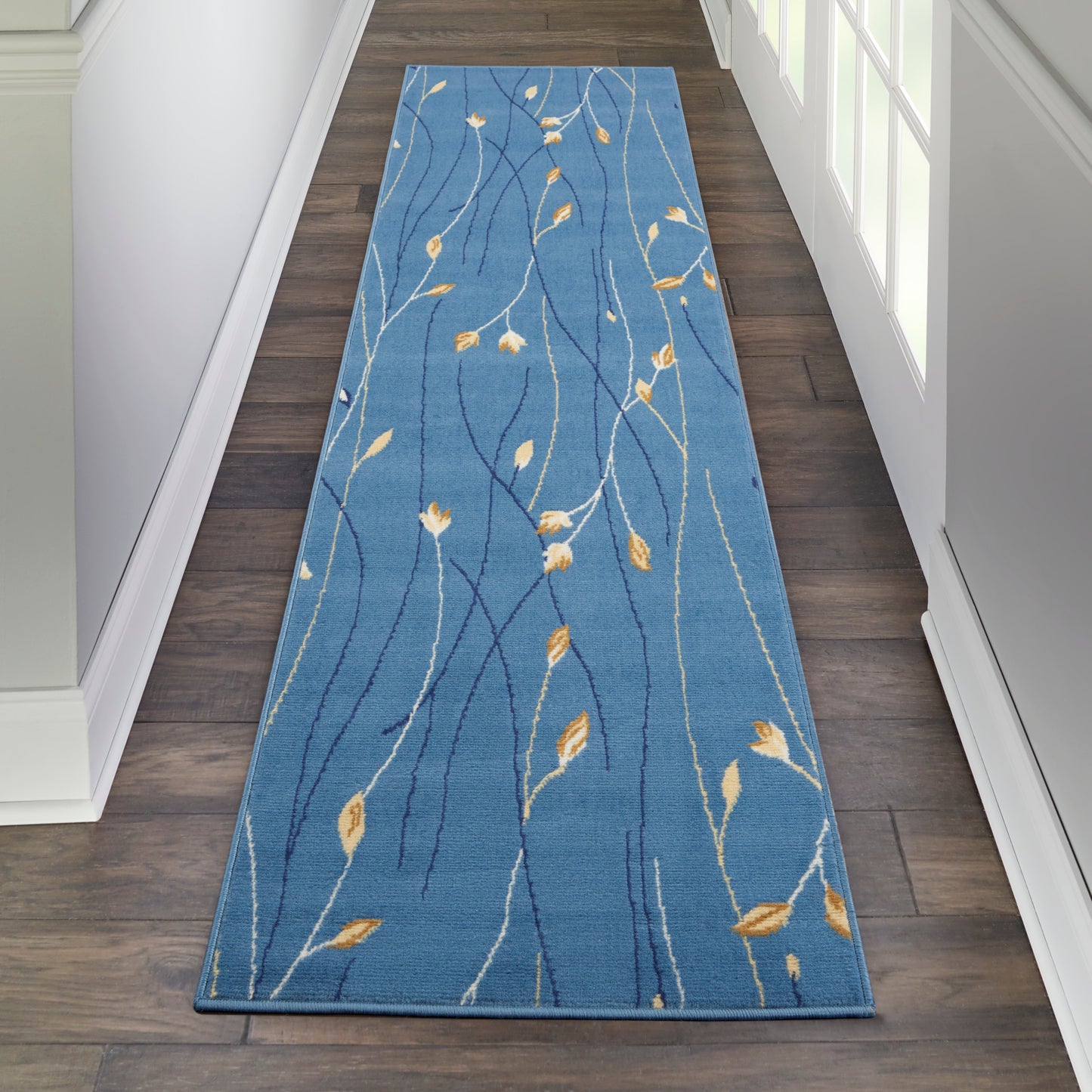 Blue hallway runner rug with white wavy stems and orange-yellow leaves, modern botanical design.