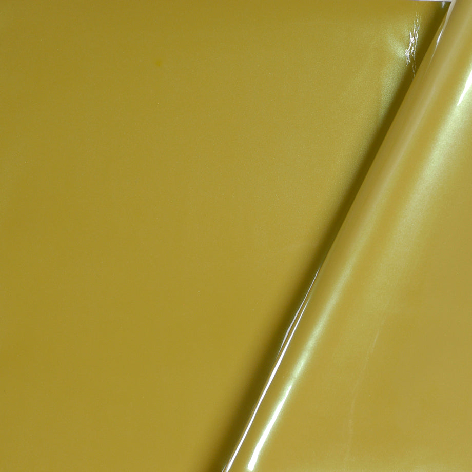 Mustard yellow upholstery fabric with a glossy finish, partially rolled at the right edge.