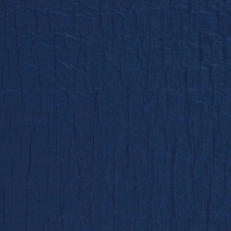 Navy blue crinkled fabric texture with subtle vertical pleats, versatile for apparel or home decor.