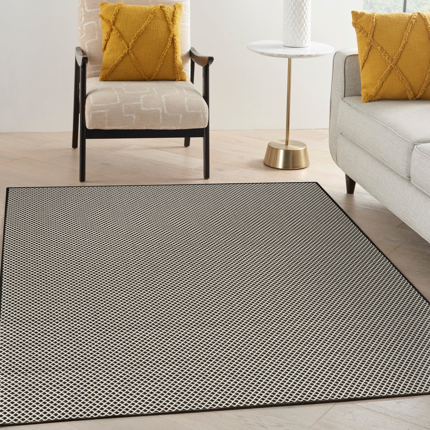 Rectangular woven area rug with a black & cream lattice pattern in a modern living room with mustard pillows.