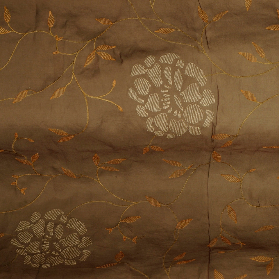 Brown fabric with gold vine embroidery, orange leaves, and pale white circular floral motifs.