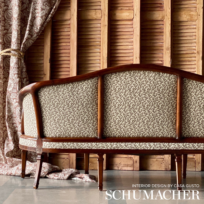 Vintage wooden-framed sofa with cream speckled upholstery, curved back, against paneled wall and damask curtains.