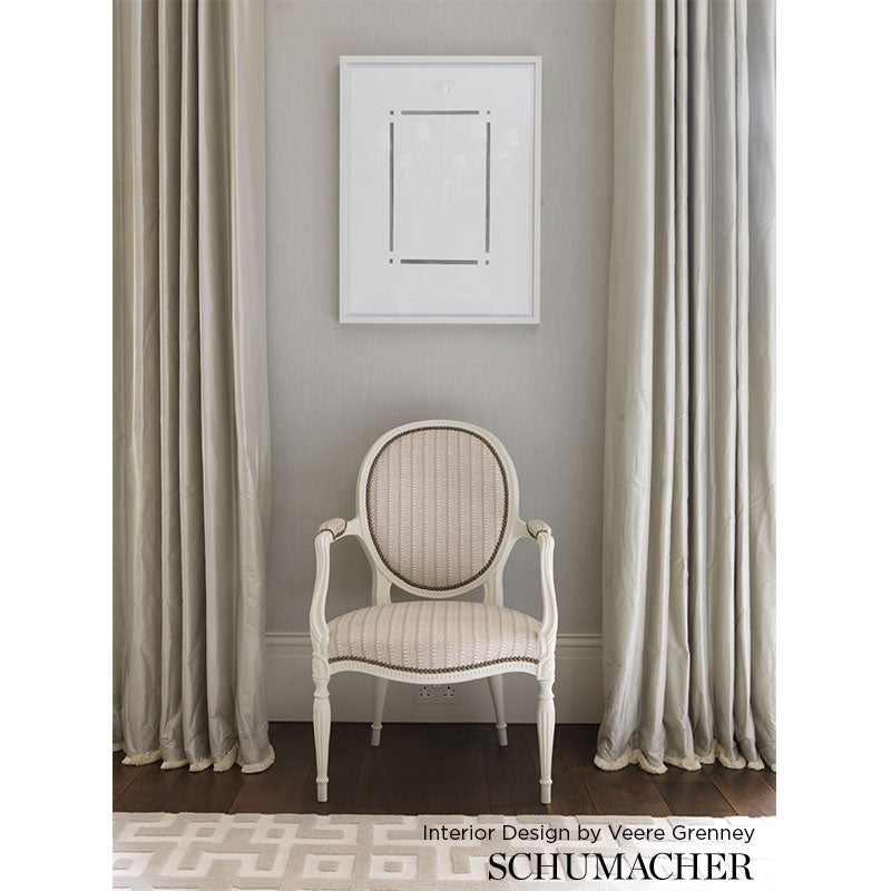 Cream oval-back Bergère chair with striped beige upholstery and carved frame, set in a neutral living room with gray walls.
