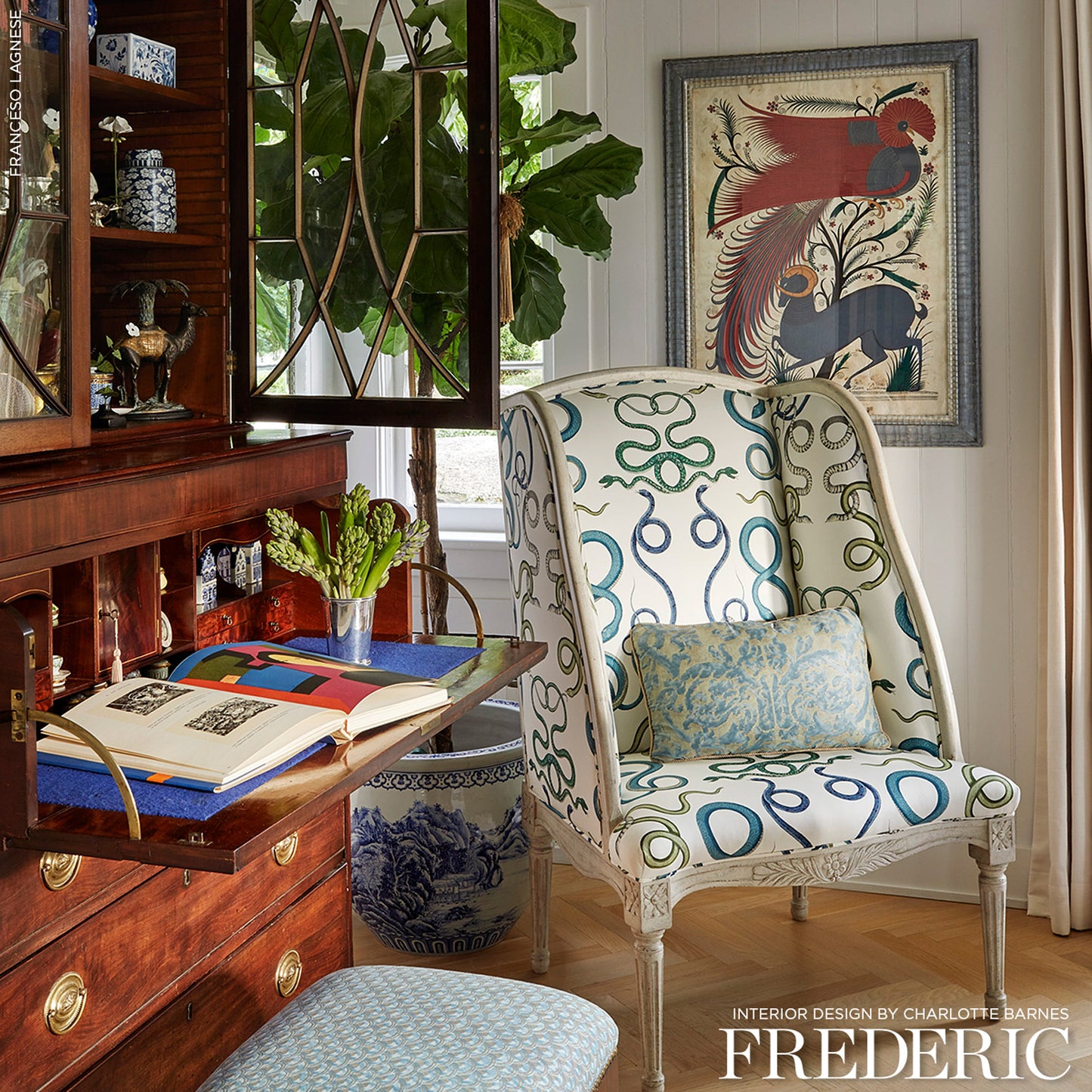 Cream wingback chair with teal-blue looped pattern and blue cushion, set beside a wooden desk and cabinet.