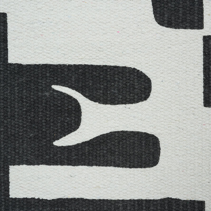 Close-up of a textured cream rug with bold black abstract curved shapes for a modern geometric look.