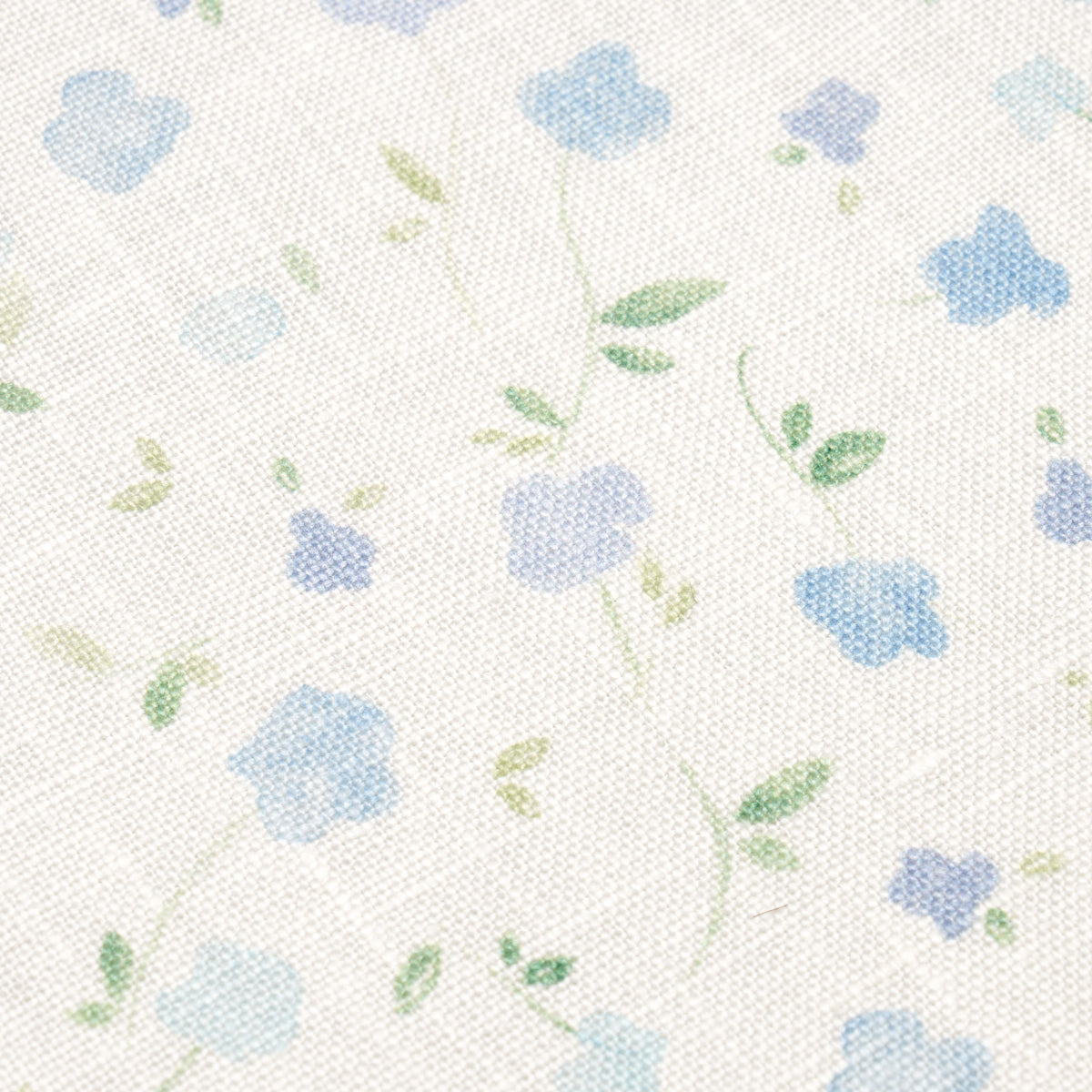 Blue textured linen fabric with a delicate floral print of pastel blue and lavender flowers and green leaves.