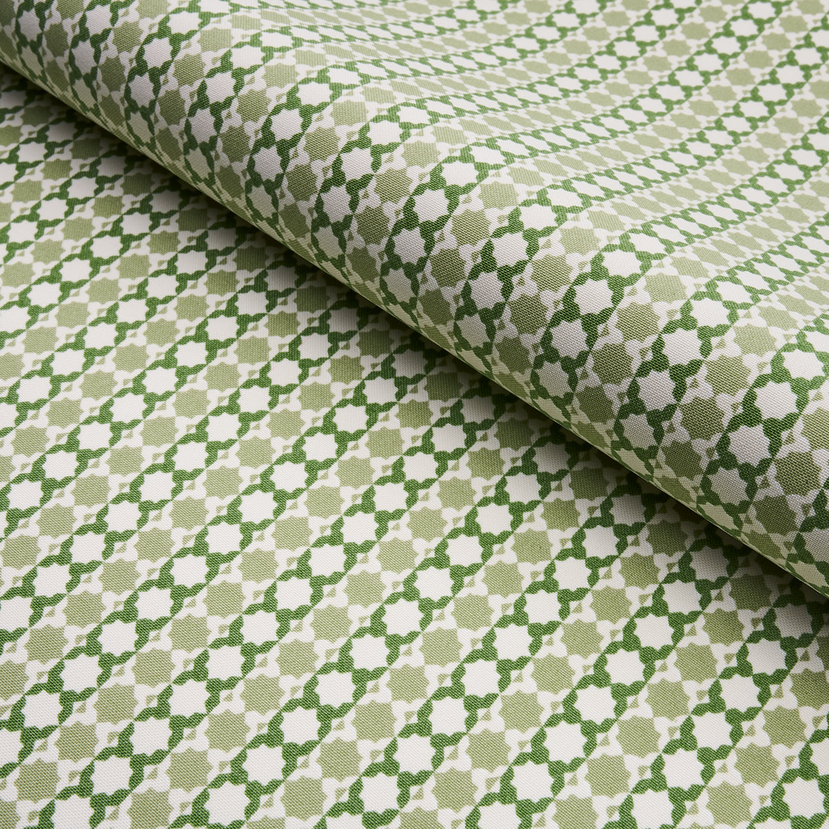 Beige woven fabric with a green geometric lattice/trellis pattern; rolled fabric sample for upholstery or drapery.