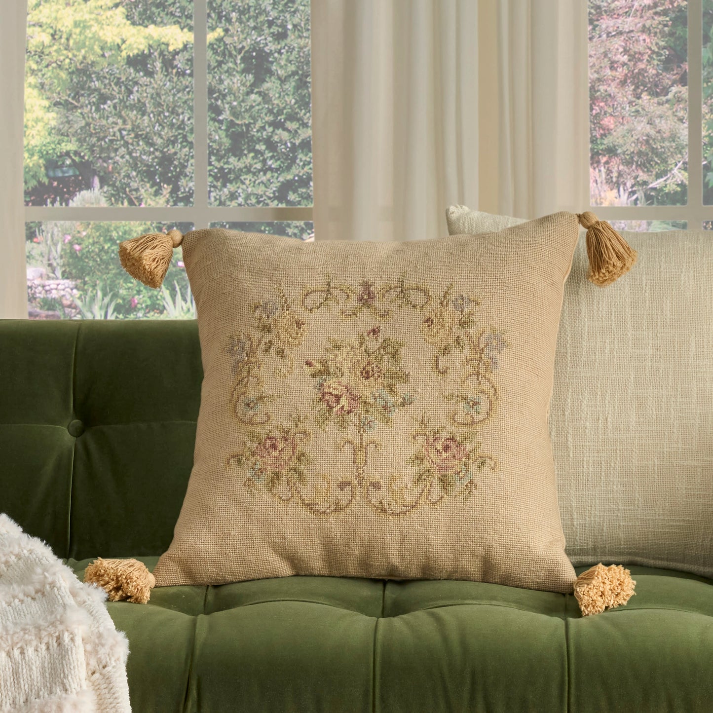 Beige tassel-corner cushion with embroidered floral motif and linen texture.