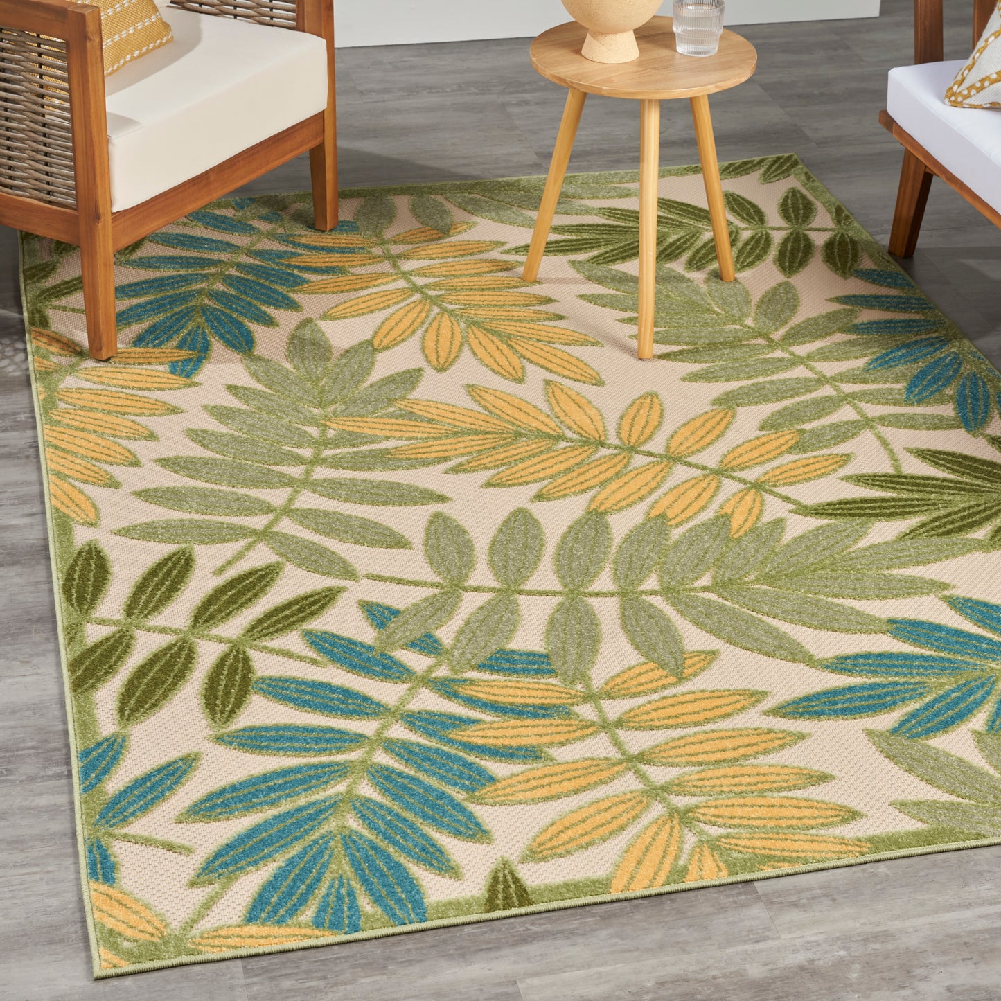 Rectangular beige outdoor rug with green, yellow & teal palm leaves pattern; woven texture.