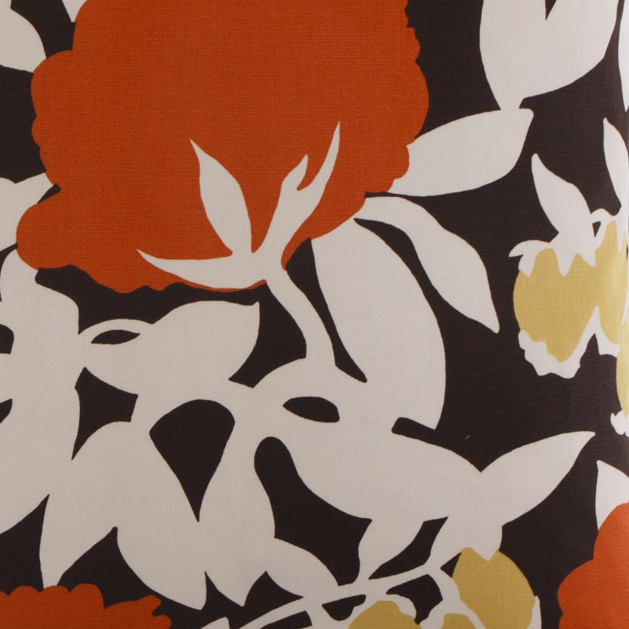 Bold floral pillow print with oversized orange bloom, yellow accent blossom, and white leaves on a dark background.