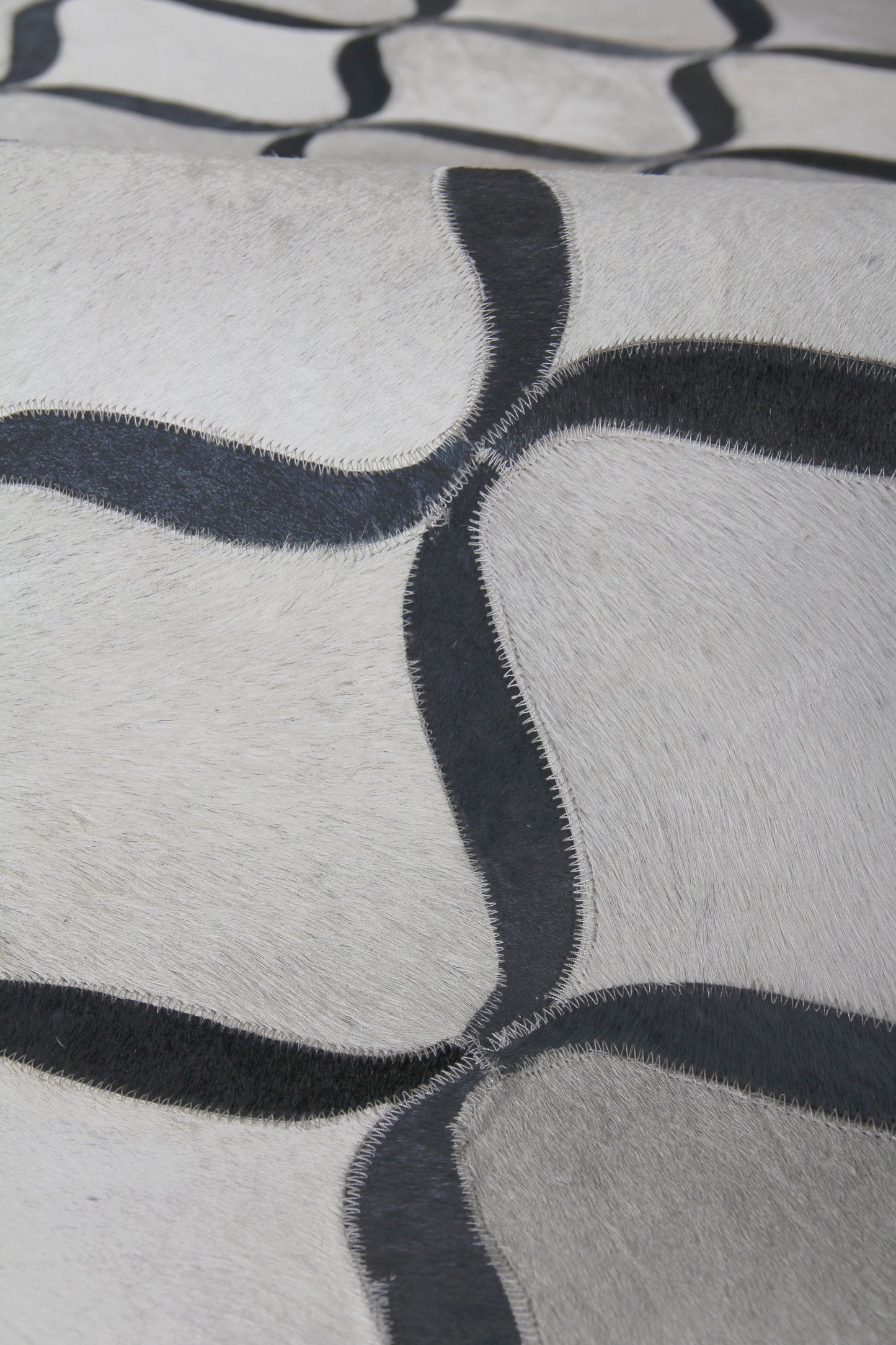 Cream natural hide rug with interlocking dark navy curved lattice pattern; indoor, hand-stitched; 4'6" x 11'.