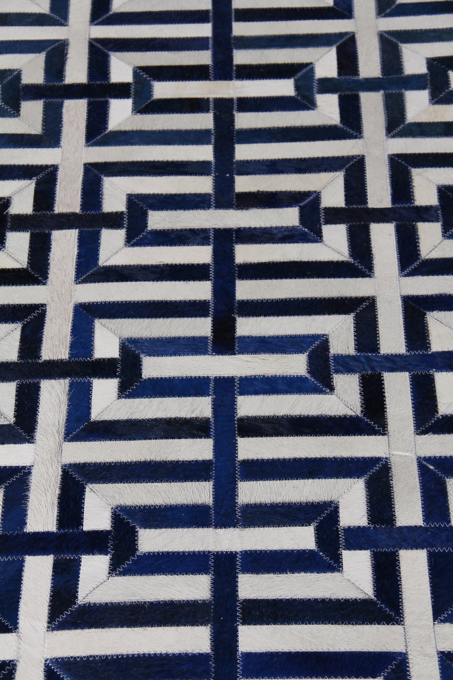 Natural hide rug for indoor use; hand-stitched with zigzag edges.