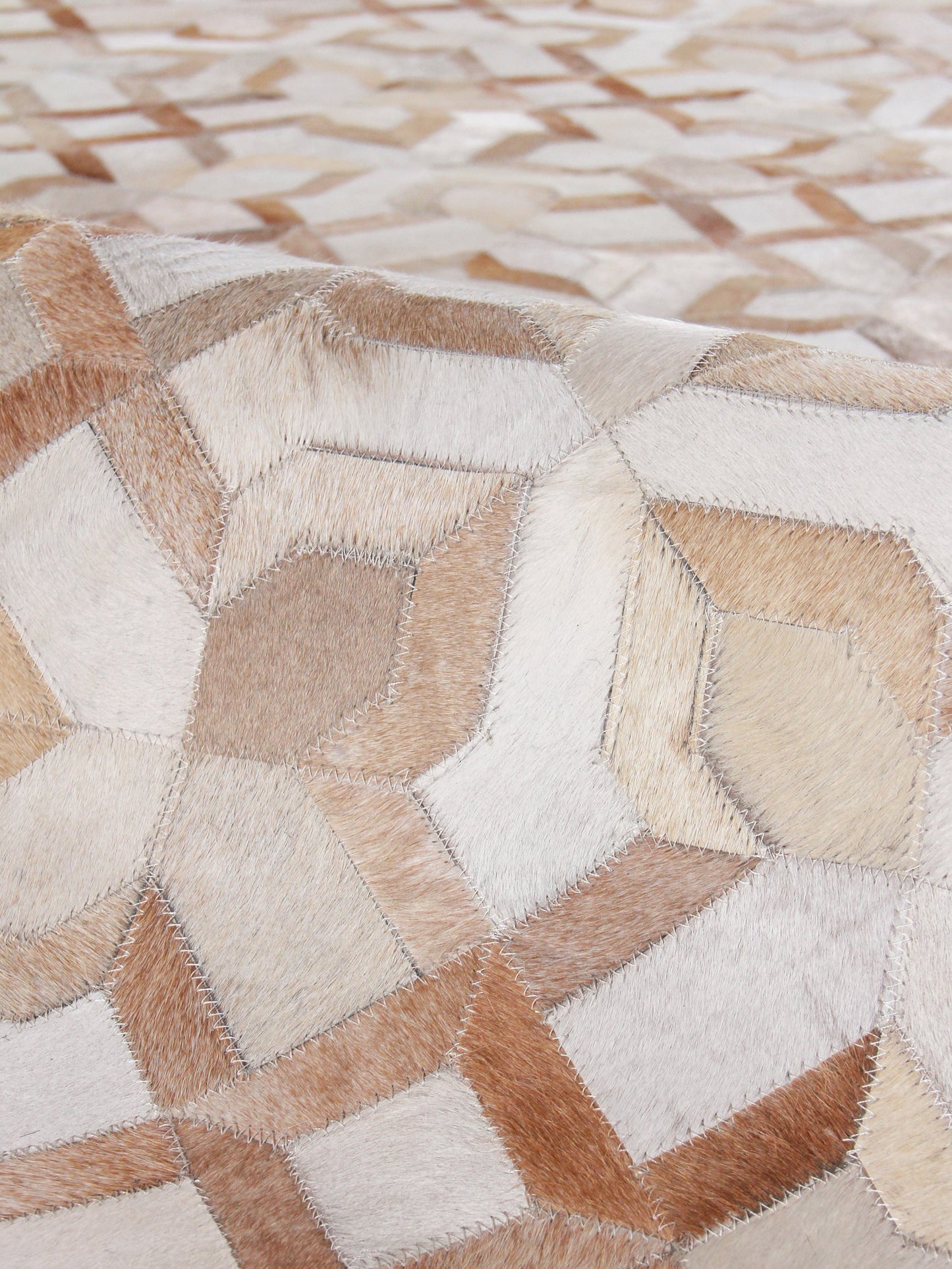 Natural hide rug; indoor hand-stitched, beige, ivory and tan geometric hexagonal patches; 5' x 8'.