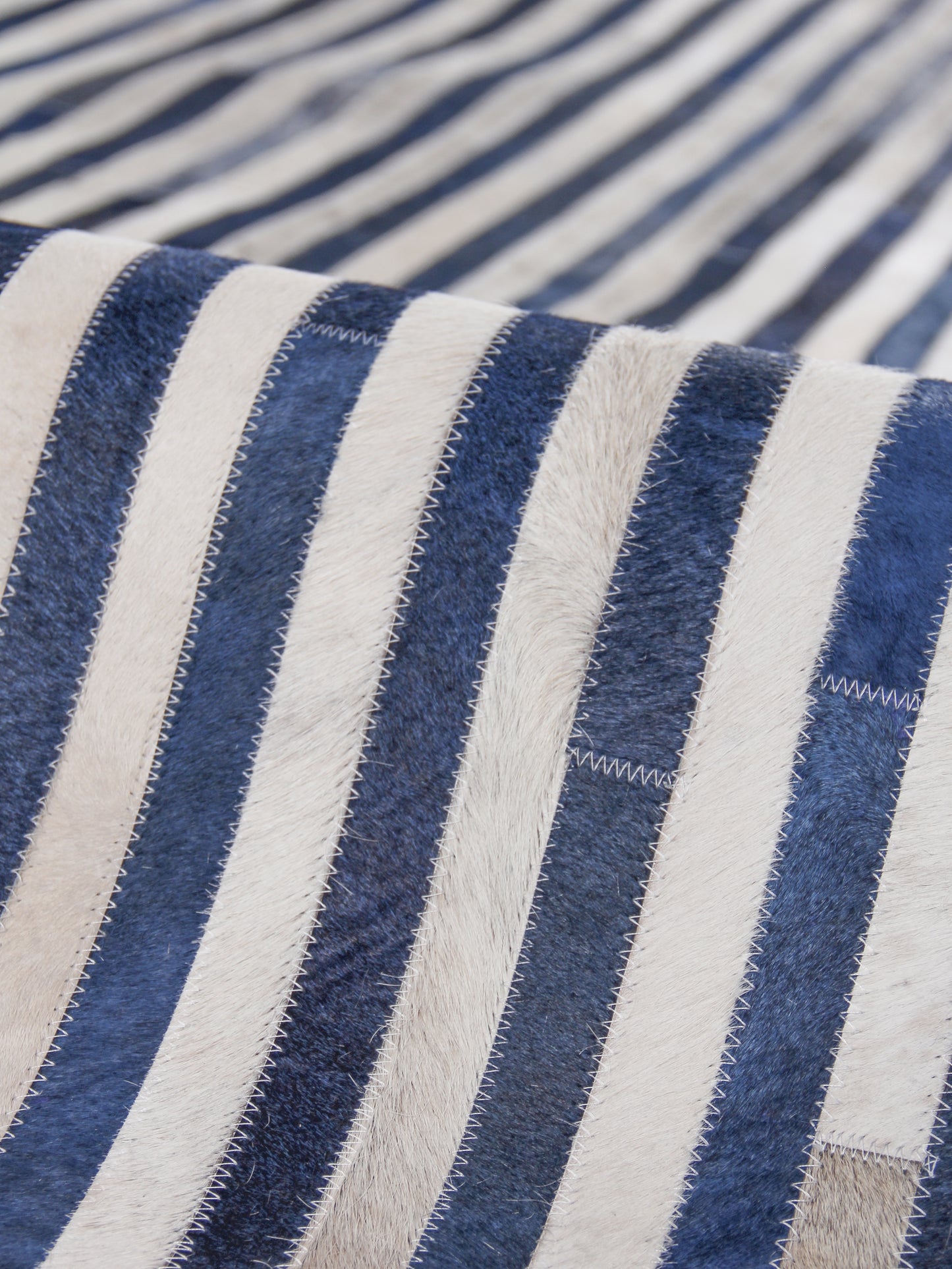 Close-up of navy and white striped rug fabric with visible hand-stitched detailing.