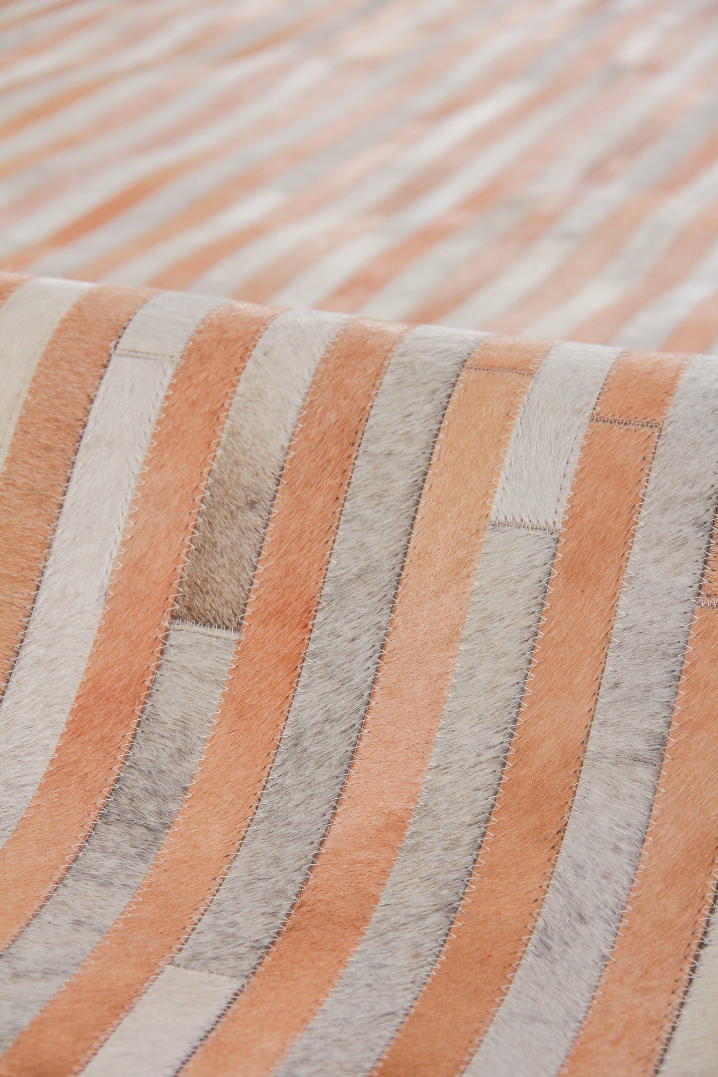 Close-up of orange & light gray striped rug with a soft woven texture.