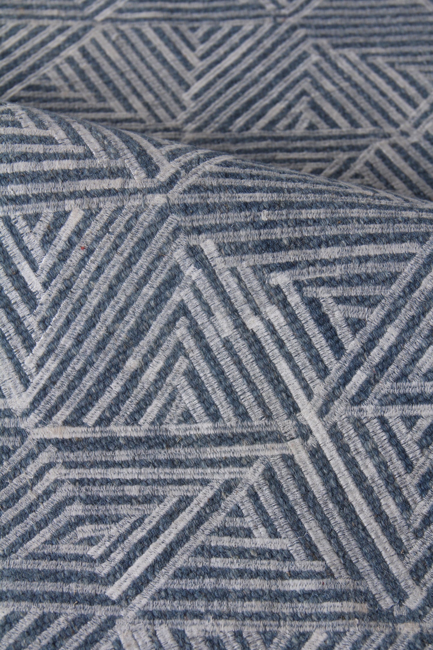 Blue & white geometric rug with concentric squares & triangles; textured woven textile for living room decor.