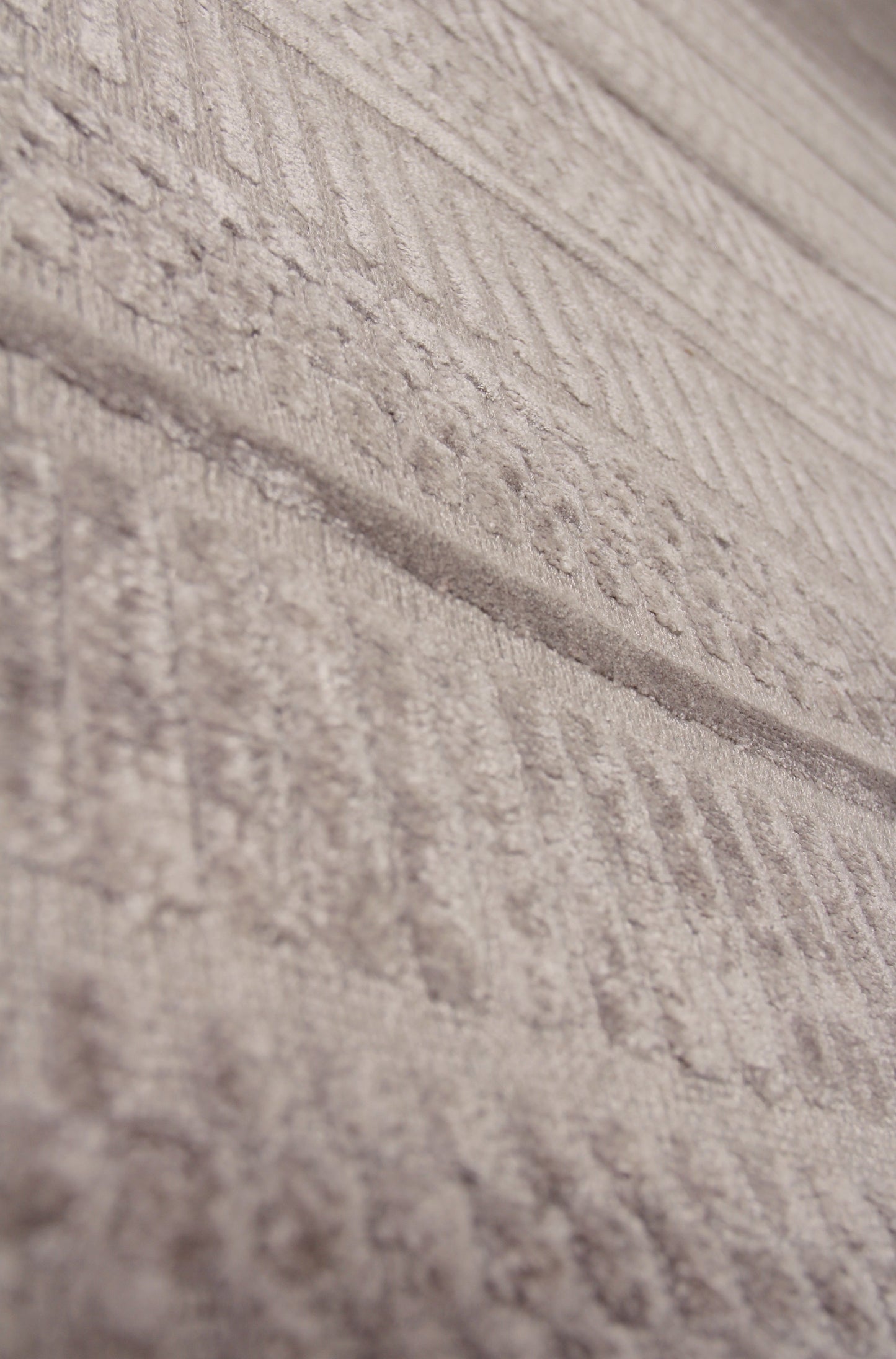 Beige hand-loomed rug close-up, showing a textured woven surface with subtle variations in the weave.