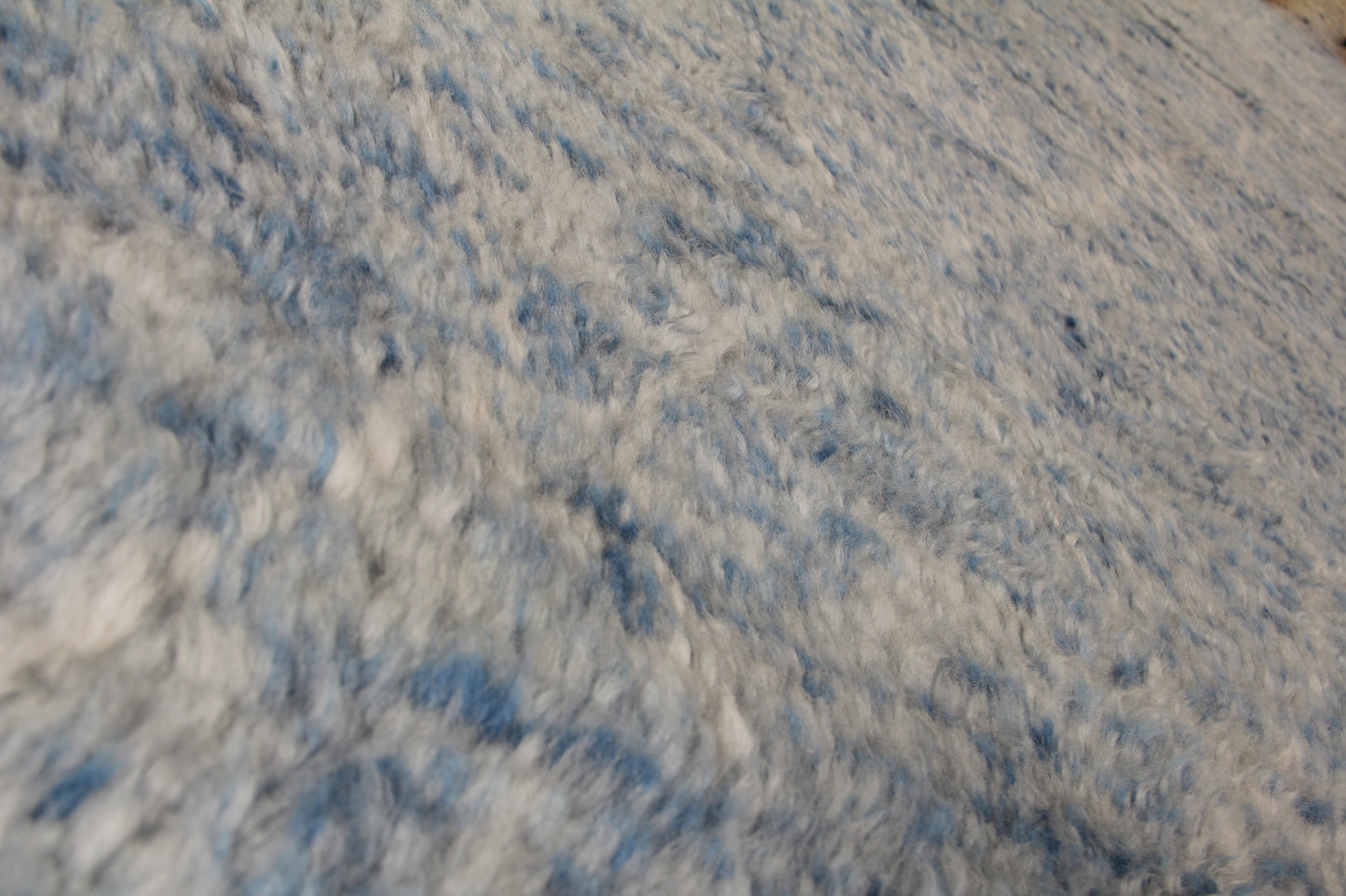 Close-up of a blue and white Moroccan indoor hand-knotted rug, showing intricate knotwork and fibers.