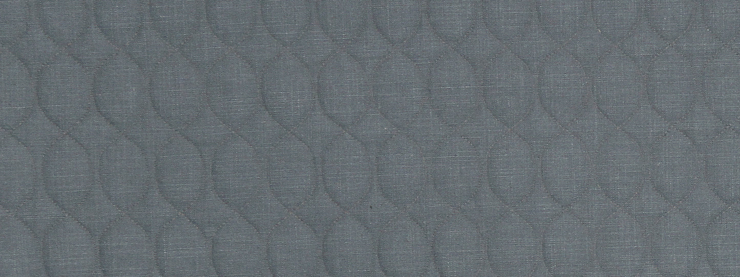 Close-up of blue-gray quilted fabric with repeating teardrop-shaped stitched pattern.