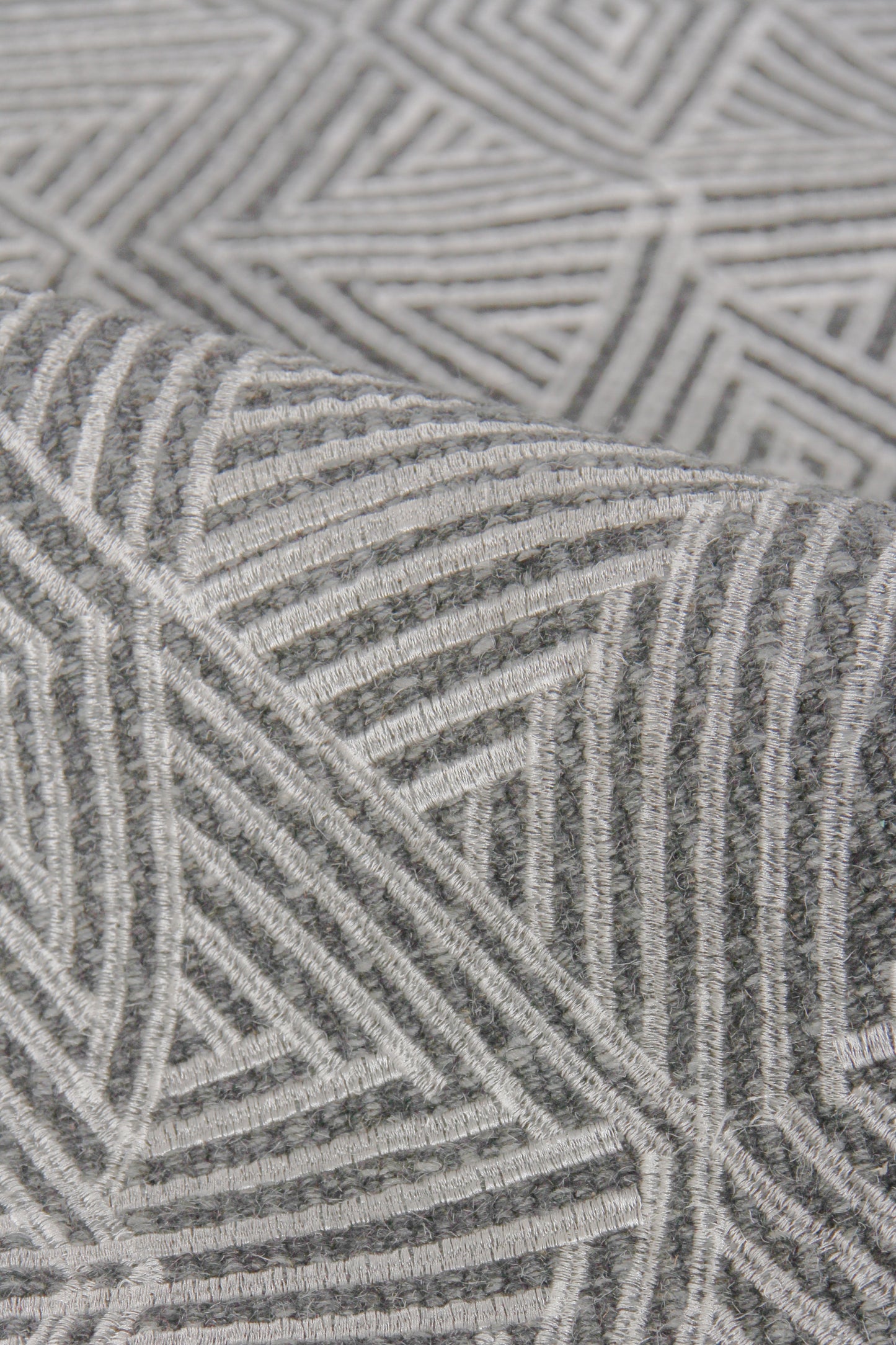 Grey geometric flat-weave rug with white linear chevron and triangle patterns; soft woven texture.