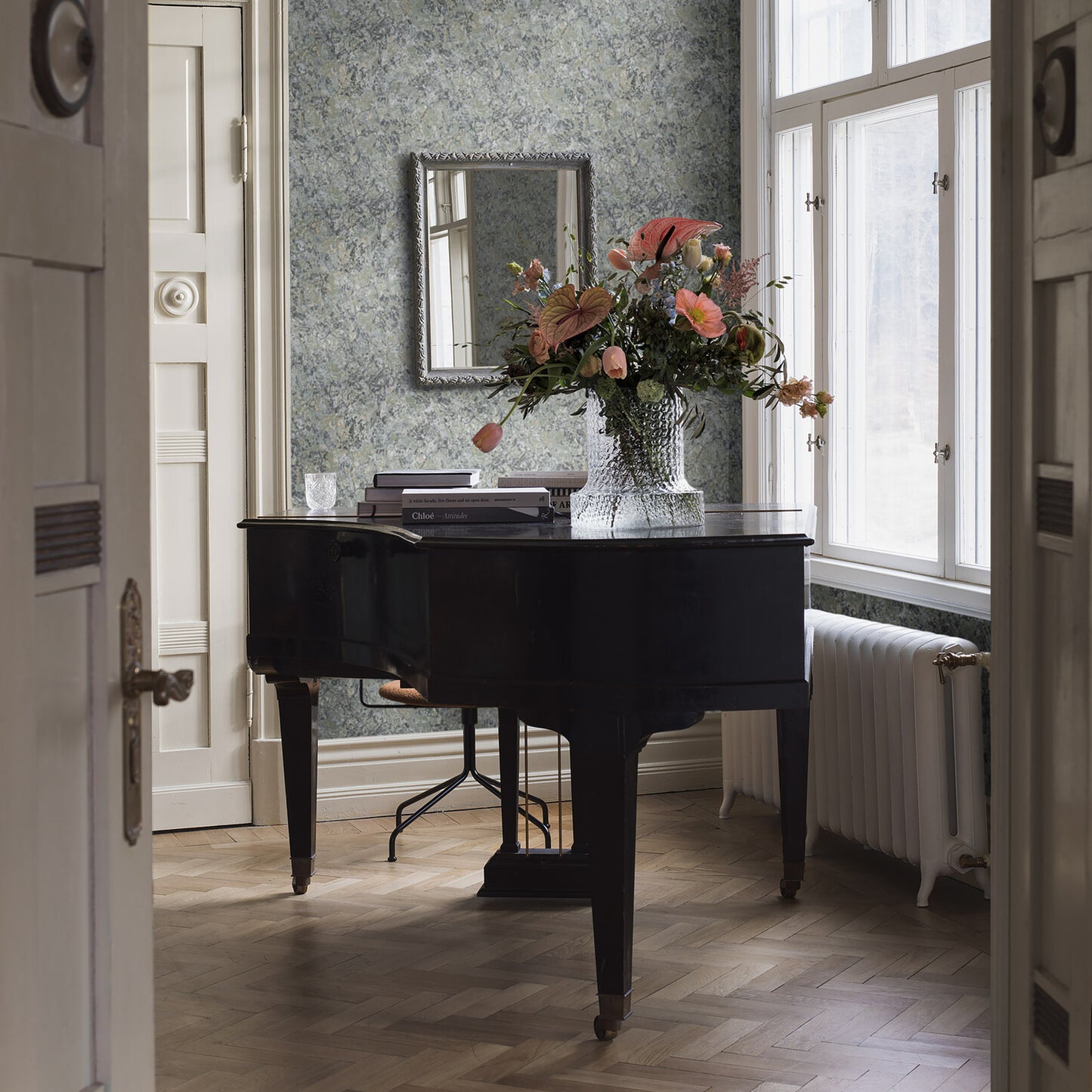 Blue patterned wallpaper on a wall in a sunlit vintage room with classic decor.