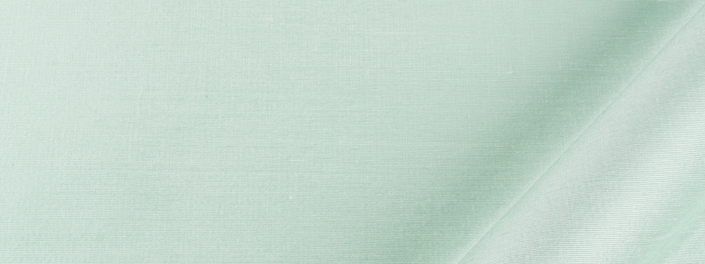 Mint green drapery fabric with a subtle weave texture and a diagonal seam or fold across the material.