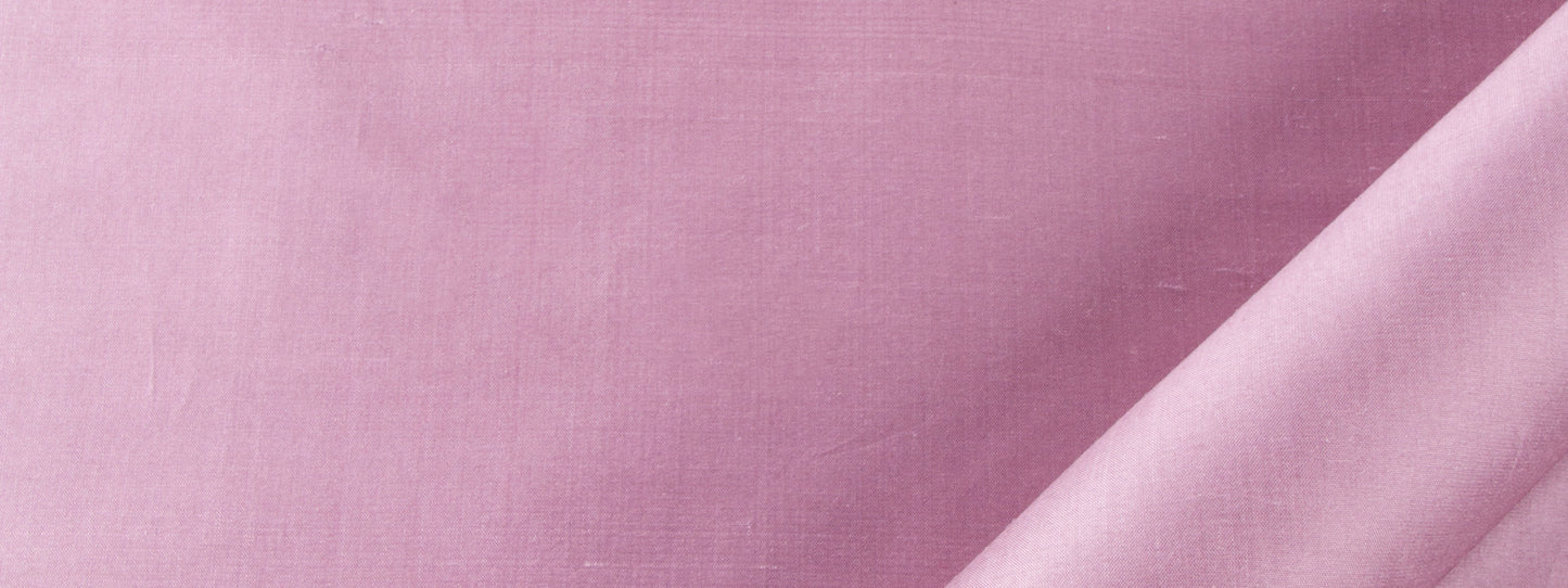 Close-up of soft pink fabric with subtle weave texture and diagonal darker pink fold.