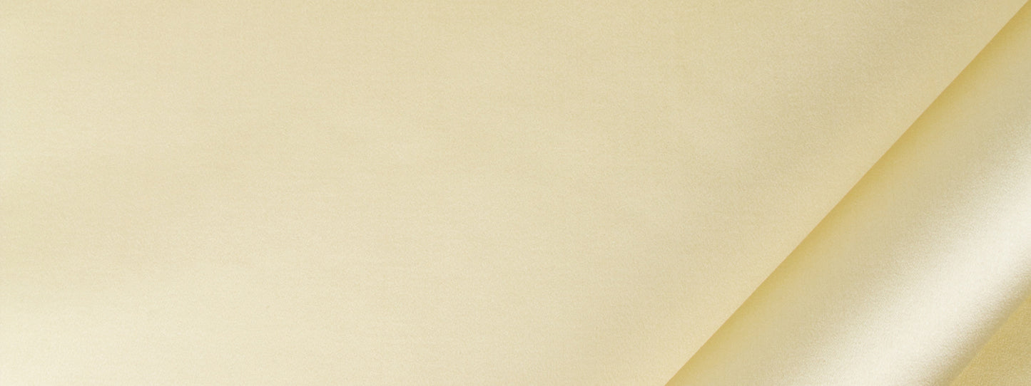 Pale yellow satin drapery fabric with diagonal fold and subtle texture.