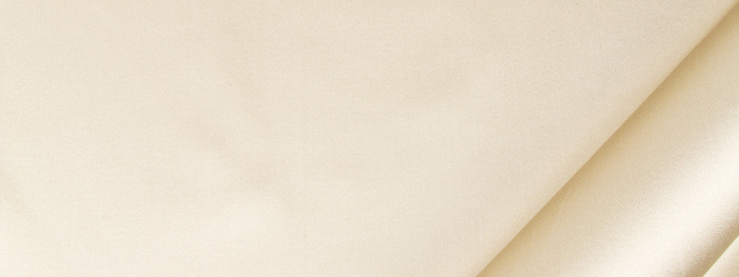 Beige fabric close-up with a diagonal crease; satin-textured textile suitable for drapery or home decor.