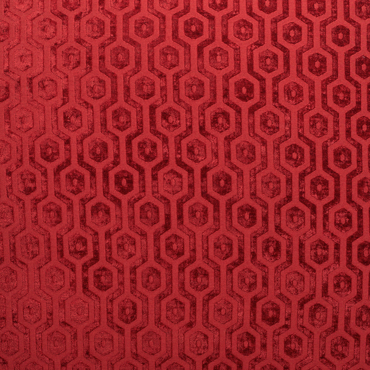 Red fabric with a repeating geometric hexagon/octagon motif in darker maroon, textured upholstery textile.