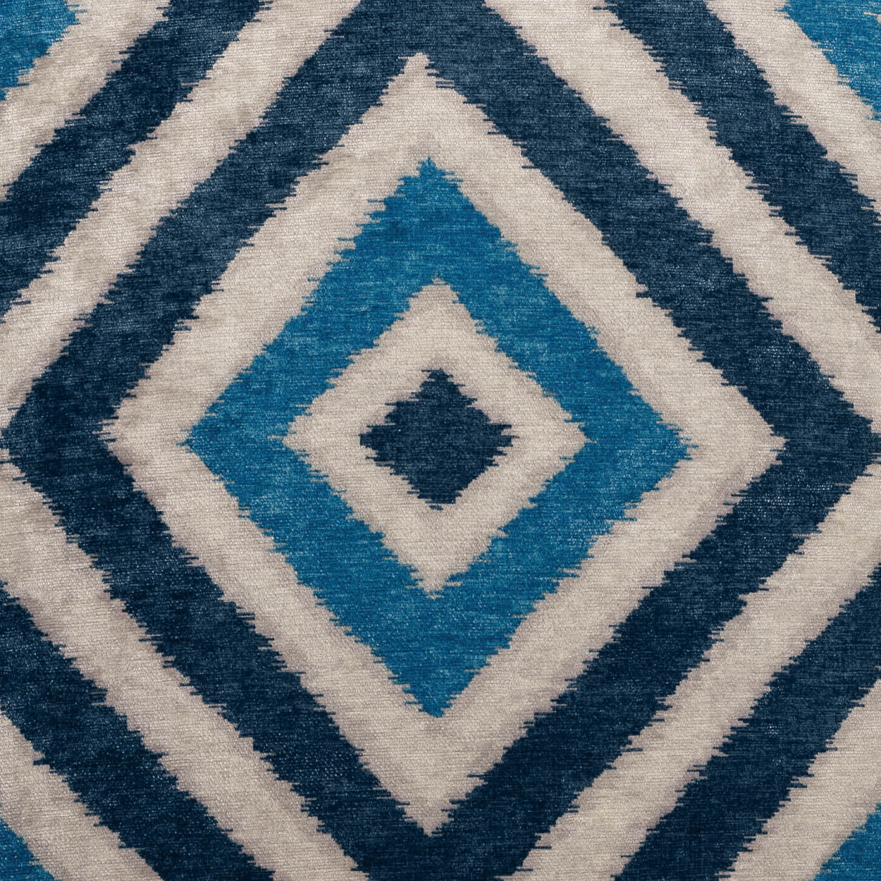 Geometric diamond-pattern pillow in teal, navy and cream; 24" x 24" square, woven textile.