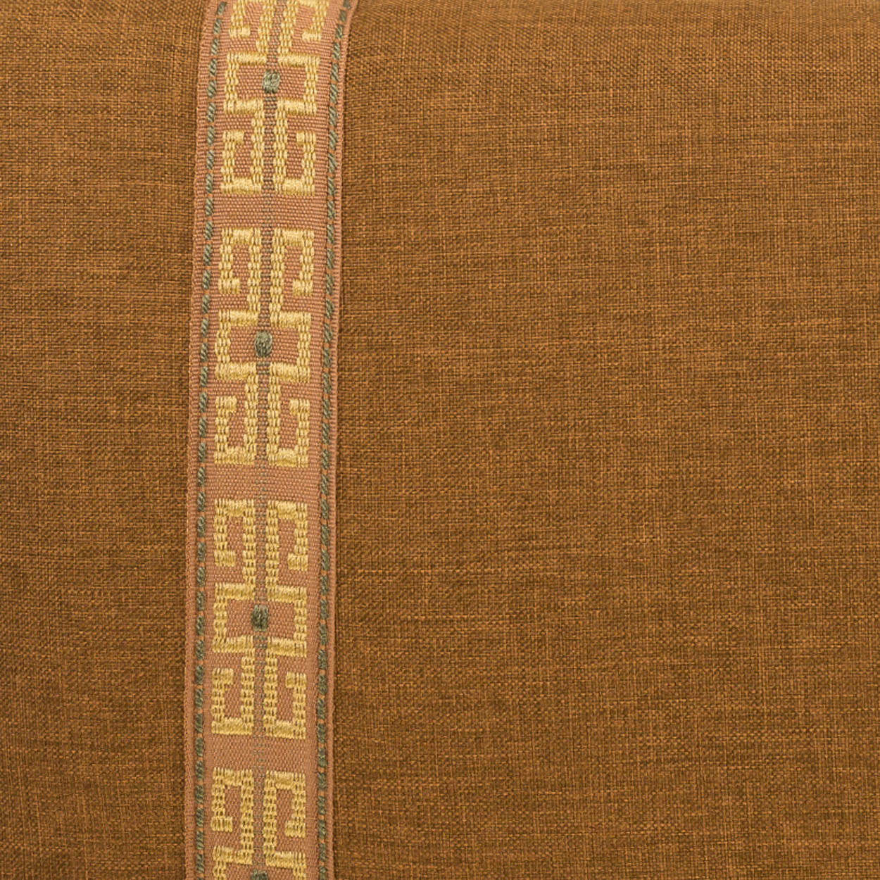 Brown textured lumbar pillow with a vertical pale yellow nugget band & ribbon trim along the left edge on a pink background.