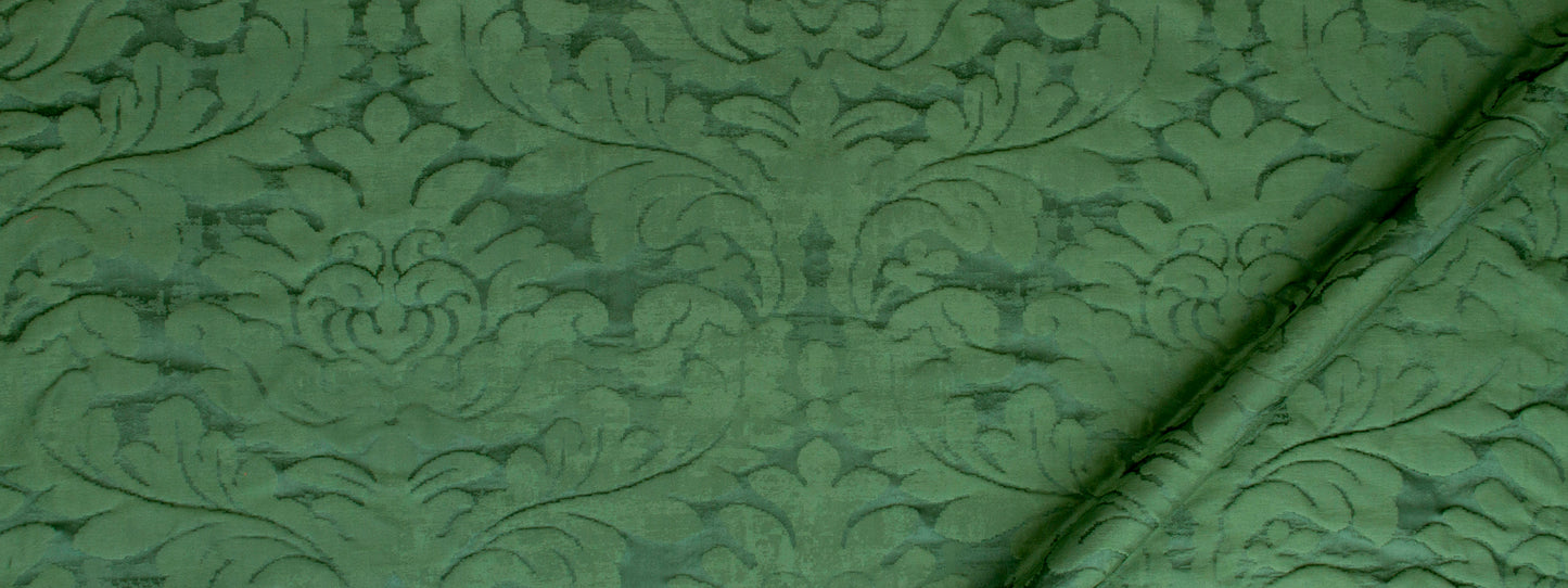 Green damask fabric with ornate floral scroll pattern and a folded edge.