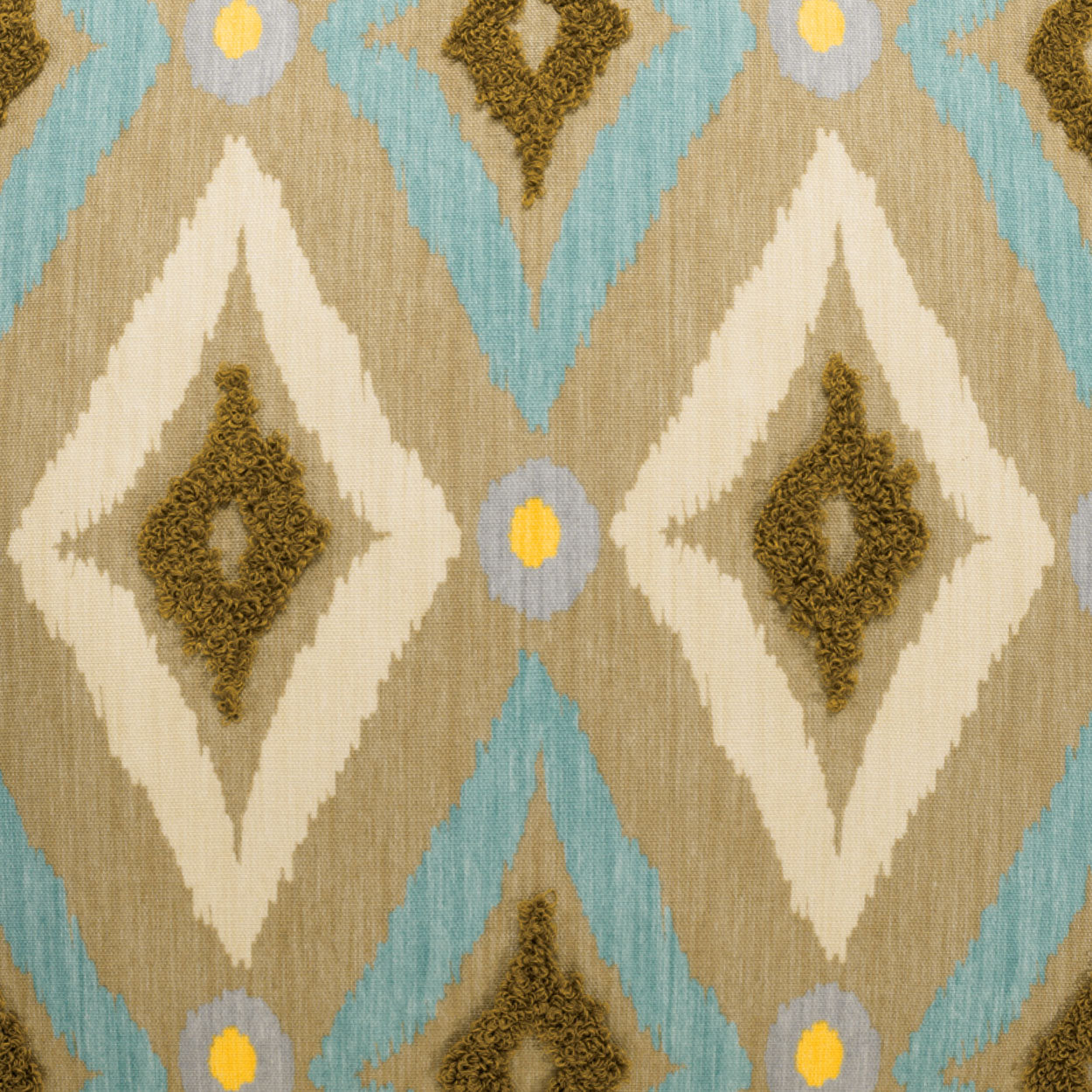 Ikat-inspired diamond fabric pattern in beige, cream, brown and turquoise with small yellow circle accents.