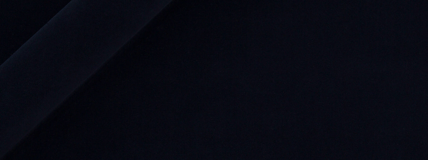 Close-up of dark navy velvet upholstery fabric with soft folds and smooth texture.