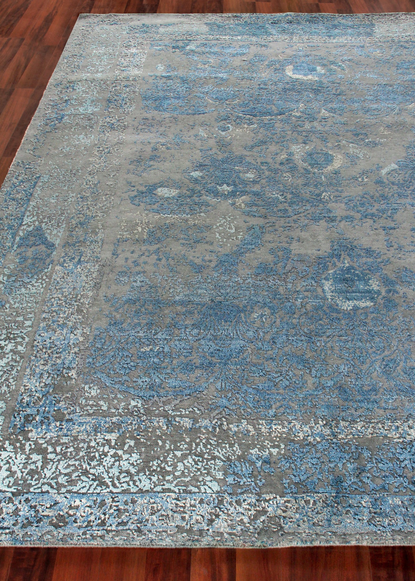Blue and gray distressed oriental area rug with floral medallion design and bordered edges.