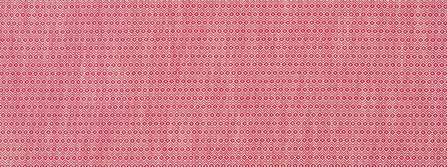 Pink upholstery fabric with tiny white diamond-shaped motifs in a repeating geometric pattern; a soft woven textile.