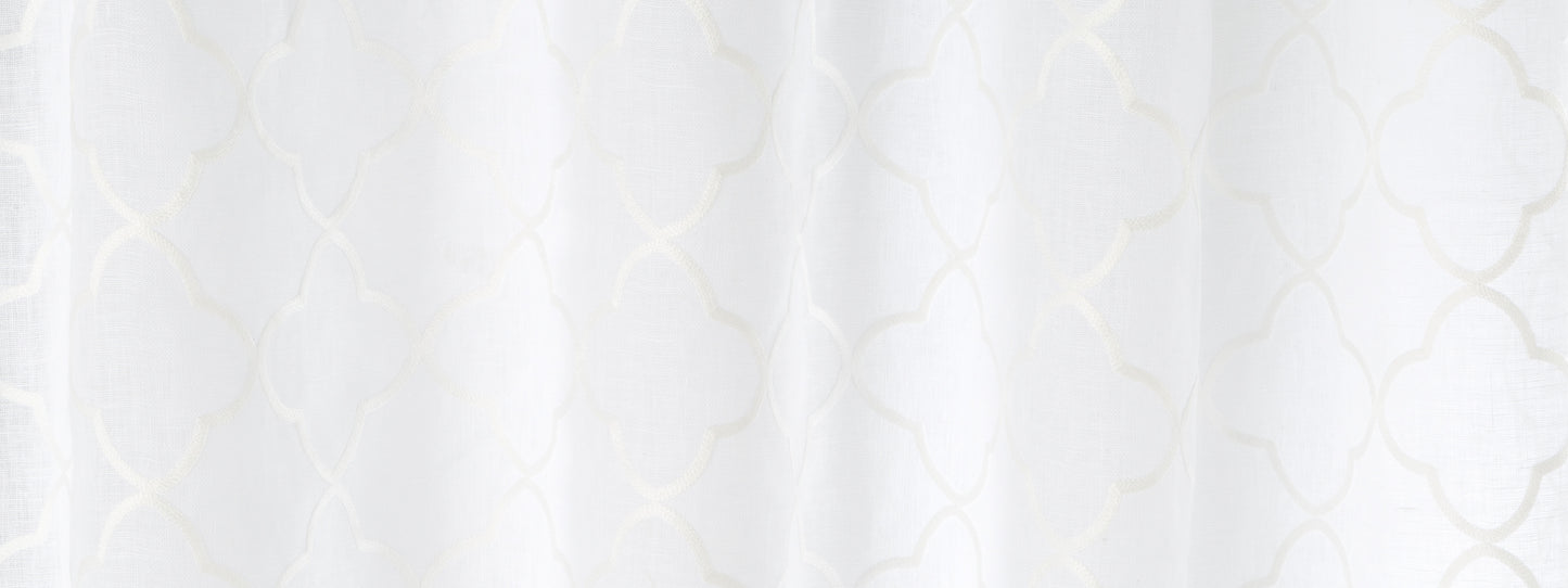 White sheer curtain with delicate quatrefoil lattice pattern and soft draped folds.