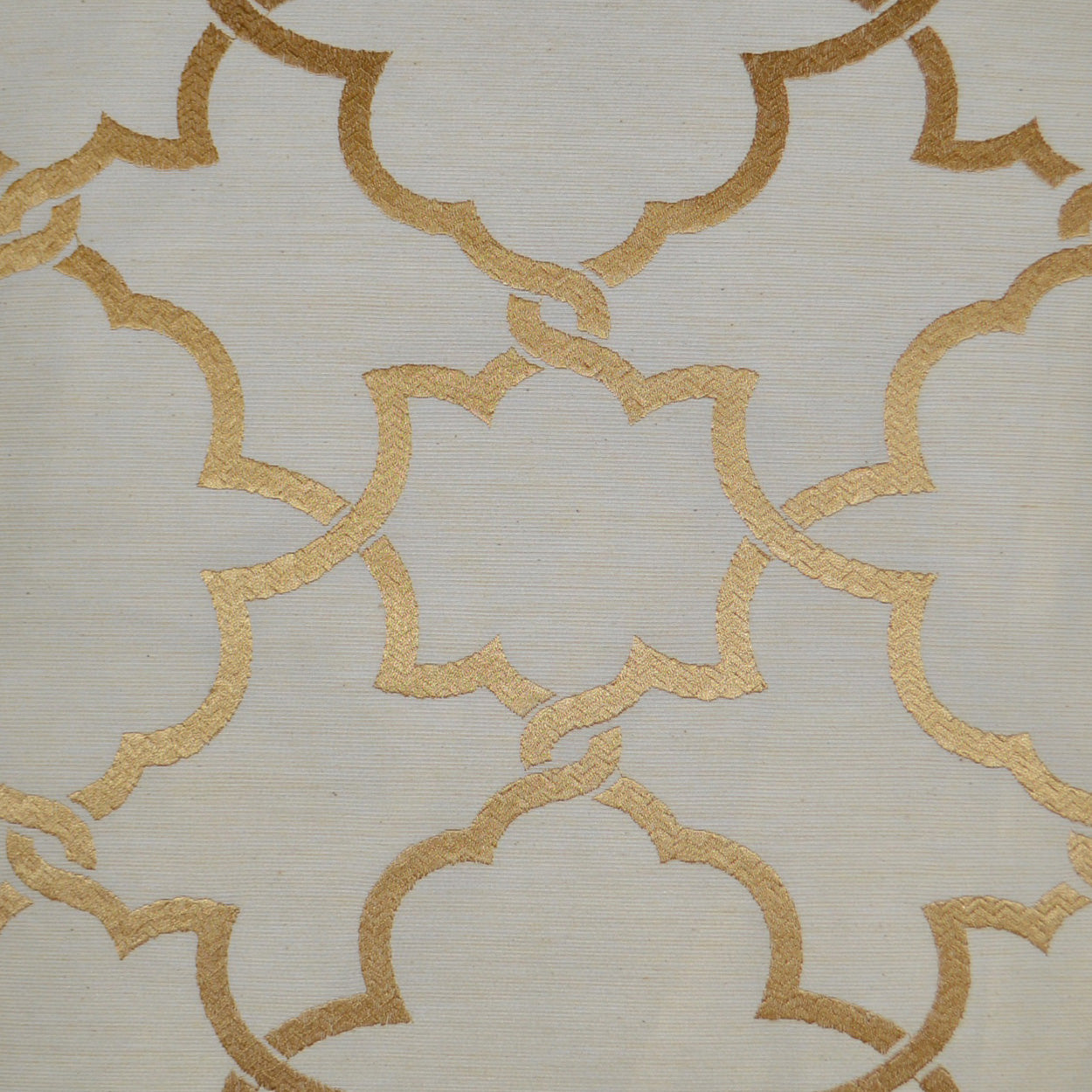 Beige pillow with gold metallic interlocking quatrefoil trellis pattern.