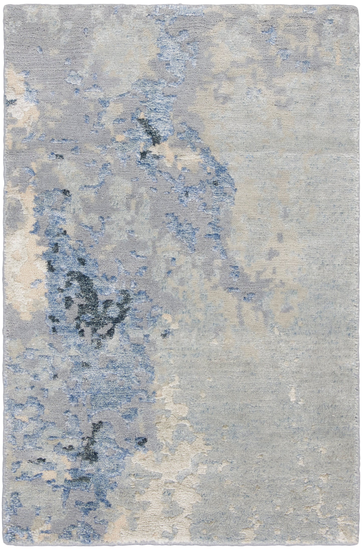 Rectangular area rug with abstract blue-gray pattern in ivory and pale blue; soft plush pile for living spaces.
