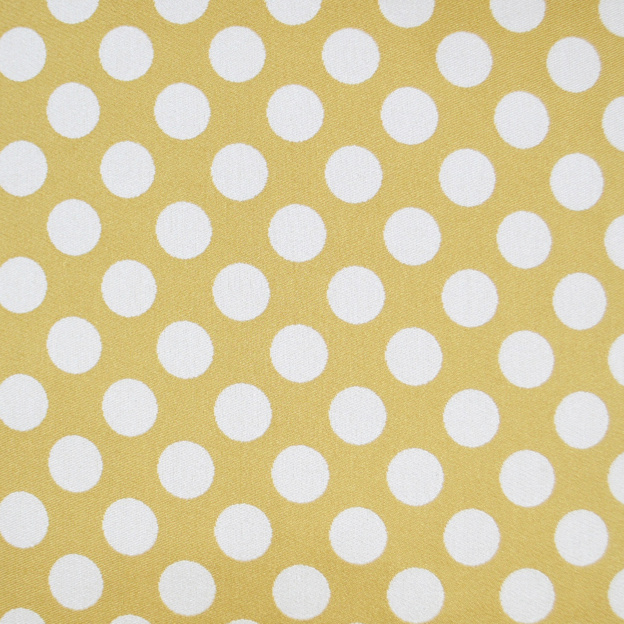Mustard-yellow pillow with white polka dots; retro style.