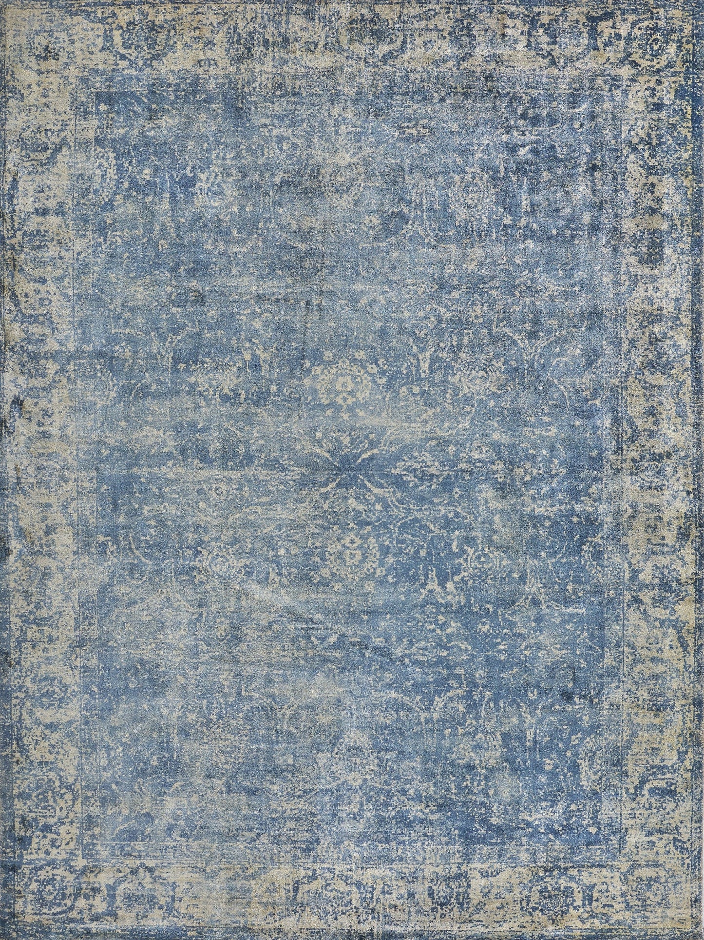 Vintage-style blue area rug featuring intricate floral patterns in lighter shades, with a distressed finish for a faded look.