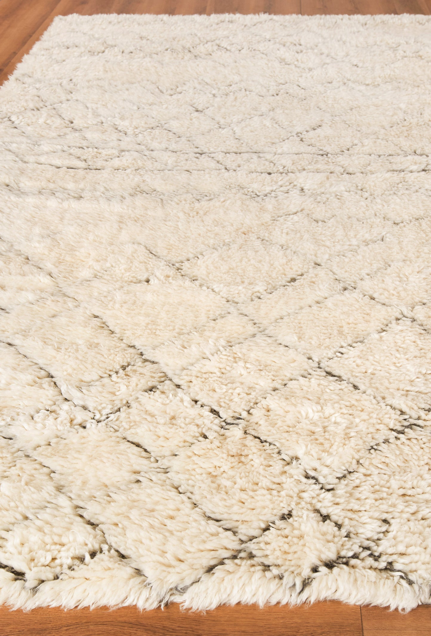 Cream hand-knotted Moroccan indoor rug with a subtle dark diamond lattice pattern on a wooden floor.