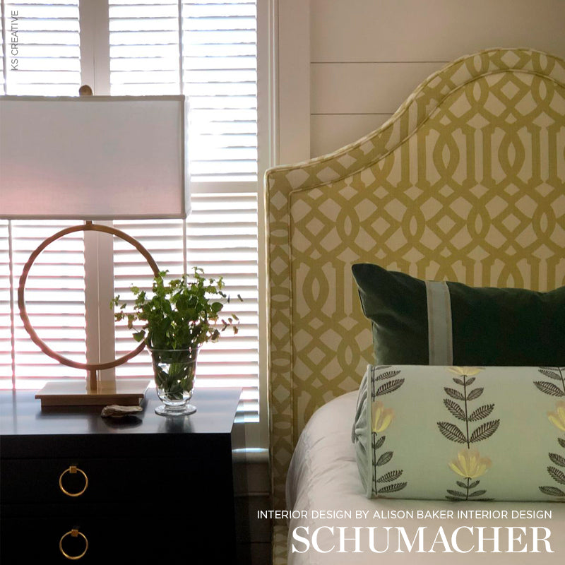 Dark wood nightstand with circular ring lamp, glass vase plant, & beige geometric headboard with botanical pillow.