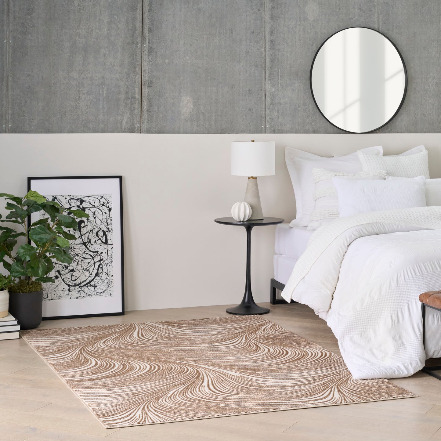 White bedding on bed with black nightstand, round mirror, abstract art, potted plant, beige swirling rug on light wood floor.